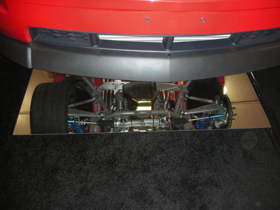 Front undercarriage of a red car shown over a mirror panel