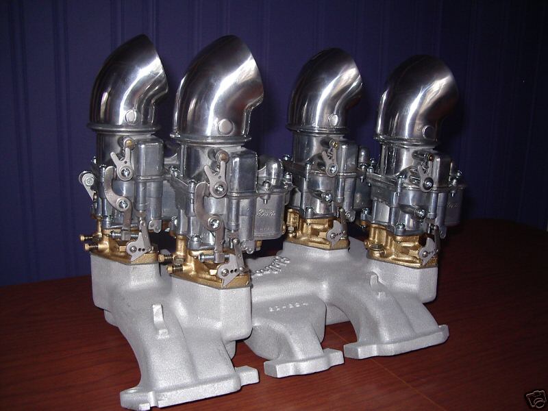 Four carburetors with chrome scoops on a polished aluminum multi-carb intake manifold