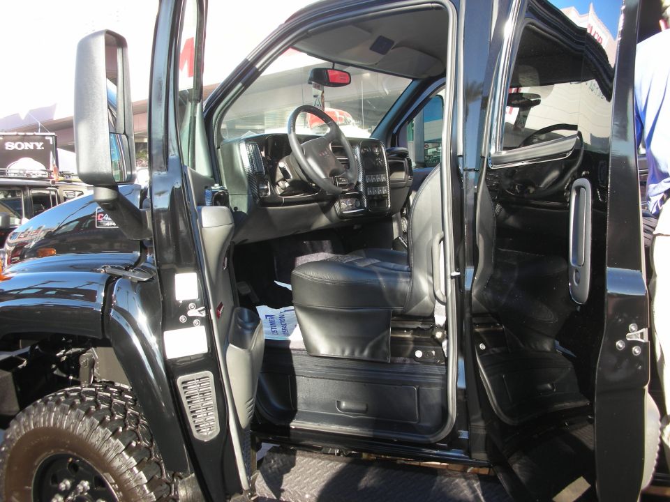Open door of a black truck showing black leather interior and steering wheel