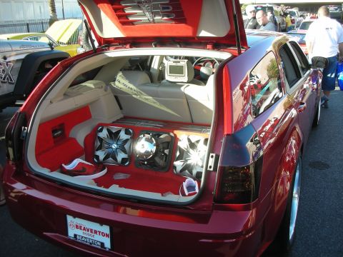 1998 Ford Crown Victoria - Open rear hatch of a maroon Dodge Magnum wagon showing a custom audio install with subwoofers and a video screen.