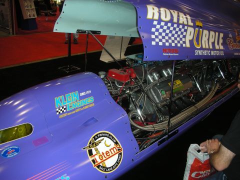 1998 Ford Crown Victoria - Purple streamliner racing car wrapped in Royal Purple and Klein Engines graphics with its engine exposed at an indoor expo.