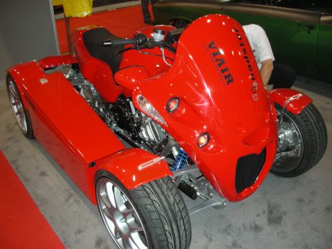 1998 Ford Crown Victoria - Red leaning four-wheeled motorcycle-style quad vehicle with twin tilting front wheels and a VIAIR decal on display.