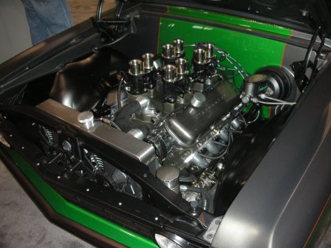 1998 Ford Crown Victoria - Polished V8 engine fitted with individual throttle-body velocity stacks in the green-and-gray engine bay of a custom muscle car.