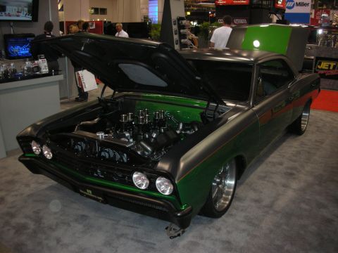 1998 Ford Crown Victoria - Custom green-and-gray muscle car shown front three-quarter with hood open exposing a stack-injected V8 at an indoor expo.