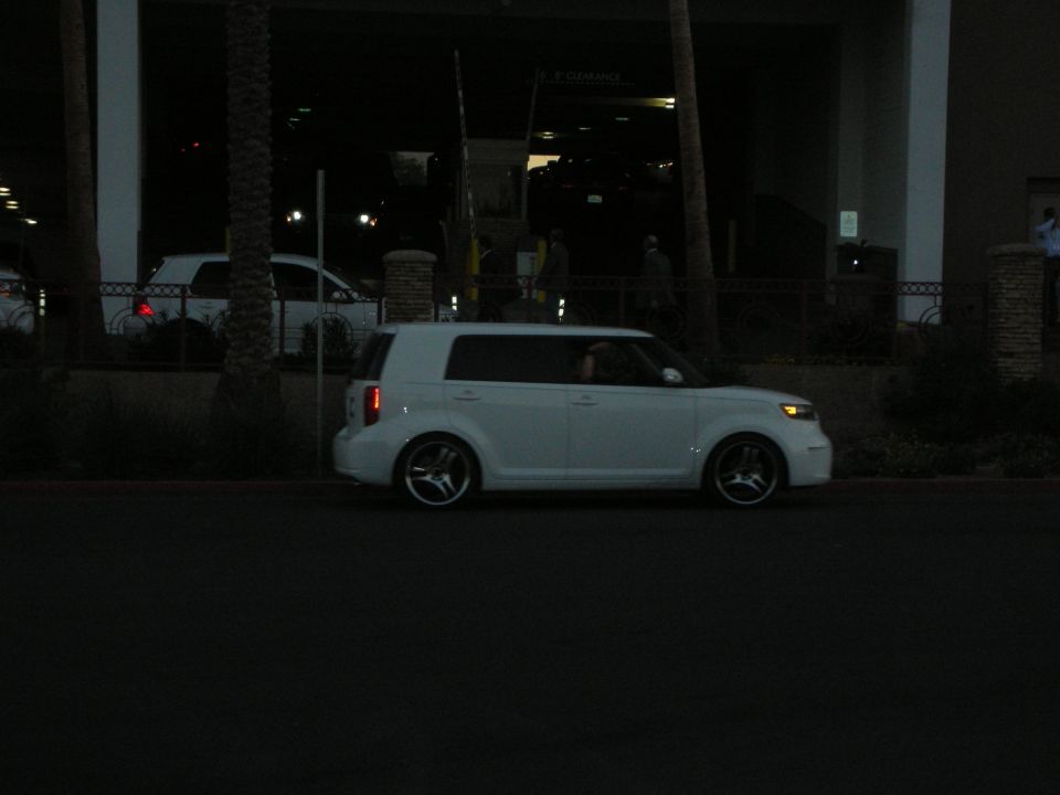 White boxy compact car parked on a street at dusk