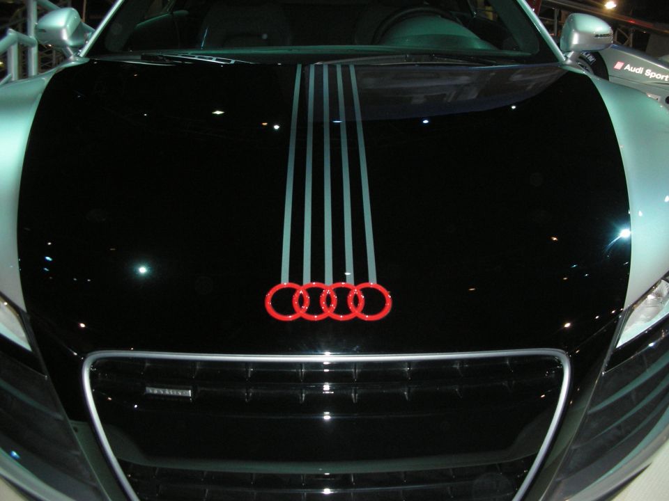 Black Audi hood with red four-ring emblem and silver racing stripes