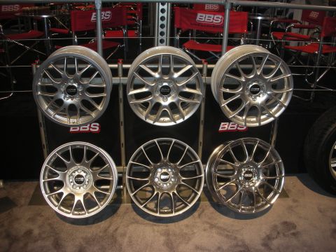 1998 Ford Crown Victoria - Six silver multi-spoke BBS alloy wheels are mounted in two rows on a black display wall above red BBS branding.
