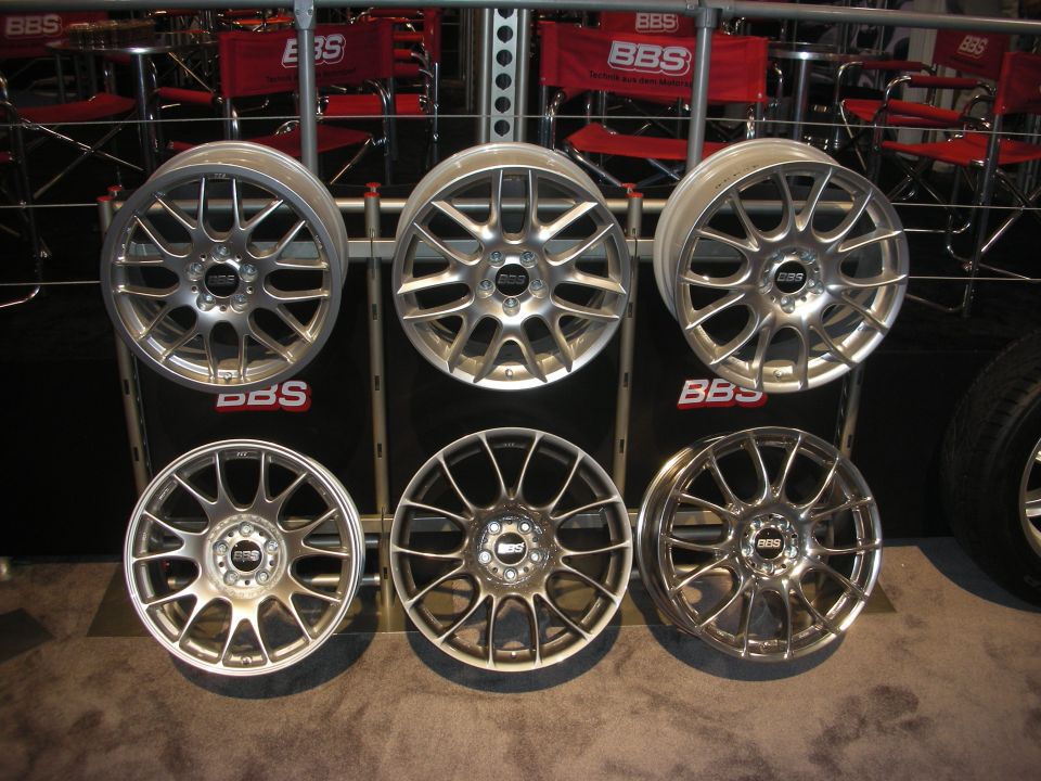Six polished BBS alloy wheels mounted on a black display wall