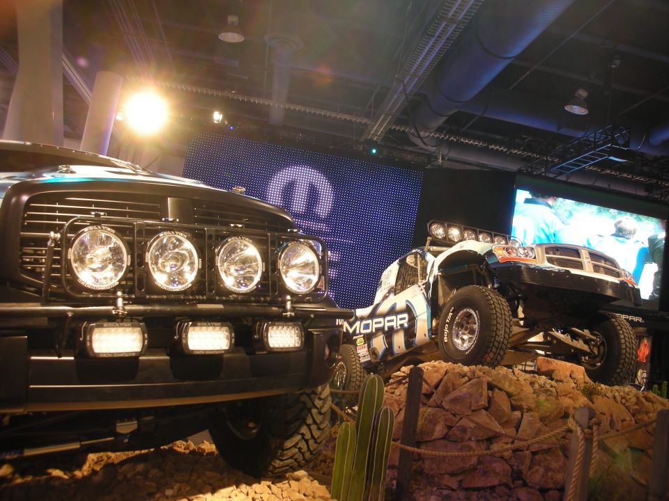 Light-bar truck and white Mopar trophy truck on staged rocks