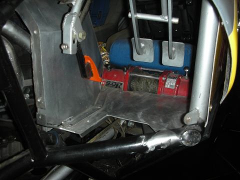 1998 Ford Crown Victoria - Close-up of a red Warn-style winch and pedal box mounted inside the welded tube frame of an off-road buggy.