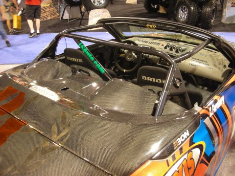 1998 Ford Crown Victoria - Open cockpit of an orange-and-carbon-fiber show car fitted with black Bride bucket seats and a welded roll cage.