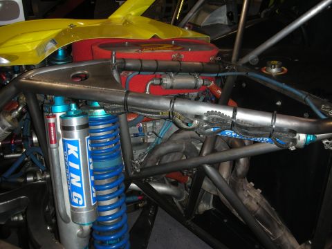 1998 Ford Crown Victoria - Close-up of a tube-frame race buggy's rear suspension showing blue King bypass coilovers and a red air filter on yellow bodywork.