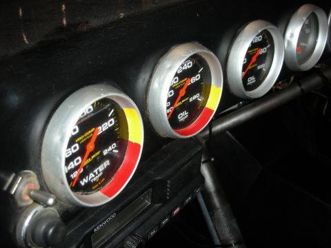 1998 Ford Crown Victoria - Angled view of a black dash with Auto Meter water-temp and oil-pressure gauges above a Kenwood head unit.