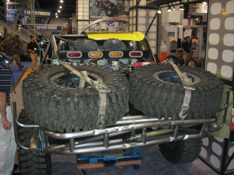 1998 Ford Crown Victoria - Rear of a tube-bumper off-road truck displaying two large spare mud tires strapped on, at an indoor show with Toyo Tires booth.