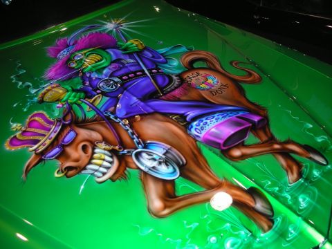 1998 Ford Crown Victoria - Detailed airbrushed mural of a costumed jester riding a horned buffalo painted over green candy-flake bodywork.