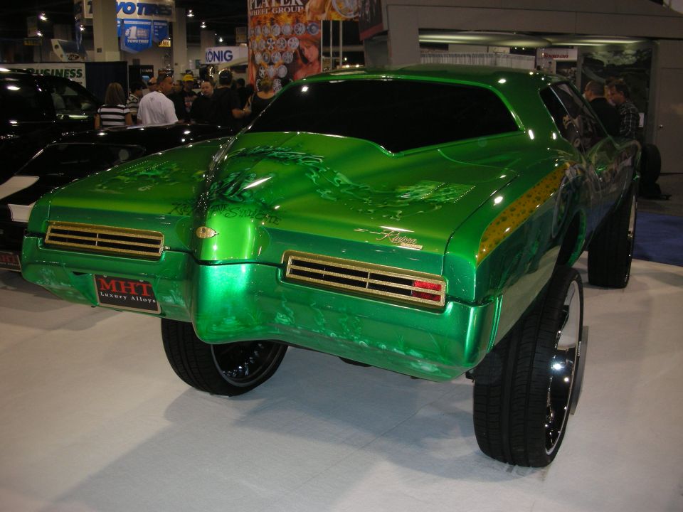 Rear of a green candy-paint custom classic coupe on big chrome wheels