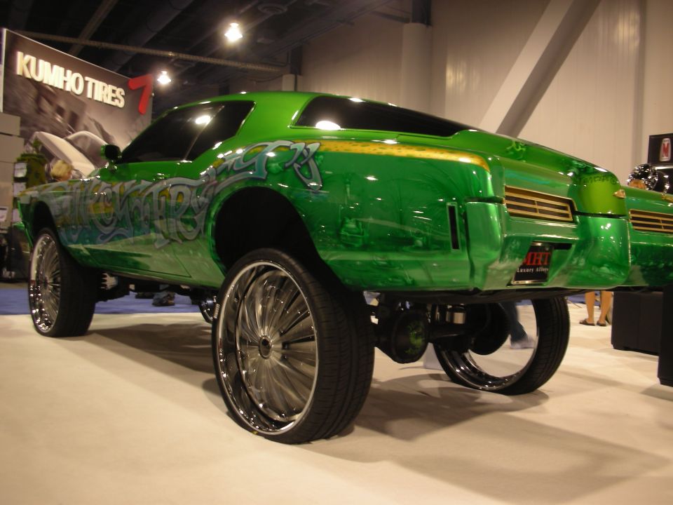 Rear three-quarter of an orange custom chopper motorcycle with wide rear tire