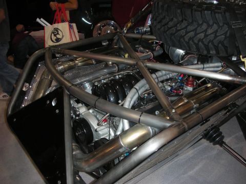 1998 Ford Crown Victoria - Mid-mounted V8 engine with stainless headers nestled inside the tubular chrome-moly frame of an off-road race vehicle.
