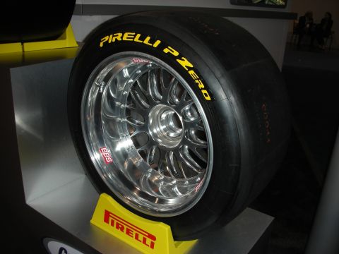 1998 Ford Crown Victoria - polished multi-spoke BBS racing wheel fitted with a Pirelli P Zero slick tire sits on a yellow Pirelli display stand.