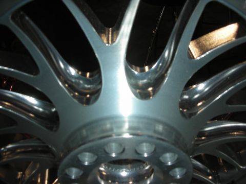 1998 Ford Crown Victoria - extreme close-up shows the polished multi-spoke center and lug-bolt hub of a chrome alloy wheel.