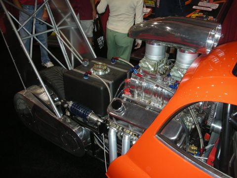 1998 Ford Crown Victoria - polished supercharged engine with twin carburetors and a blower sits exposed in the rear of an orange custom show car.