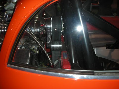 1998 Ford Crown Victoria - Looking through the rear glass of an orange custom car reveals a polished engine and chrome components in the bay.