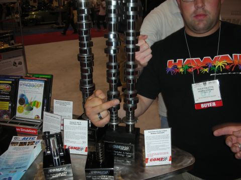 1998 Ford Crown Victoria - man wearing a Hawaii shirt and a Buyer badge holds upright performance camshafts on a COMP Cams booth display.