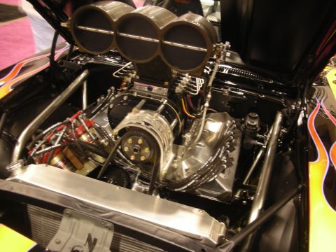 1998 Ford Crown Victoria - Front view of a supercharged engine topped with three large round velocity stacks and a polished blower, set in a flame-painted bay.