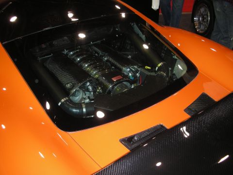 1998 Ford Crown Victoria - View through the rear glass of an orange supercar showing a mid-mounted engine with carbon-fiber surrounds.