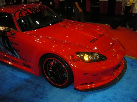 1998 Ford Crown Victoria - Front three-quarter view of a red Honda S2000 with wide body panels, black wheels, and assorted tuner brand decals.