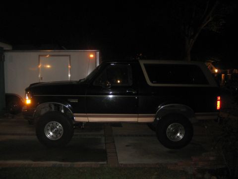 1994 Ford Bronco - A black SUV is parked outside at night, showing its side profile.