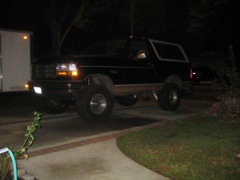 1994 Ford Bronco - A black Ford Bronco is parked in a driveway at night, illuminated by its headlights.