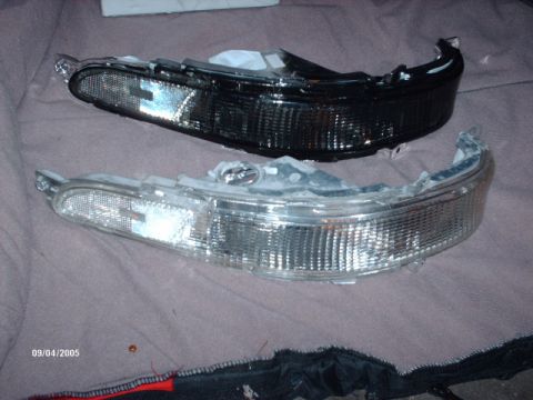 1995 Ford Probe - A clear and a blacked-out car headlight are displayed side-by-side on a fabric surface.