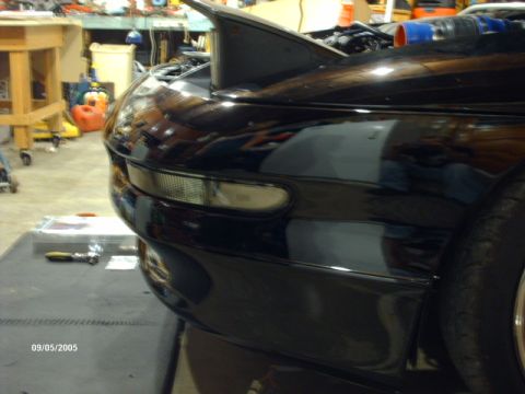 1995 Ford Probe - A black sports car is parked in a garage, showing its front corner and fender.