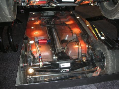 1998 Ford Crown Victoria - Mirror-floor display showing the underside of a vehicle with a copper-toned underbody, suspension, and braided lines.