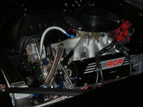 1998 Ford Crown Victoria - polished V8 engine with a single carburetor, RCR-branded valve cover, red coil, and braided fuel lines in a dark engine bay.