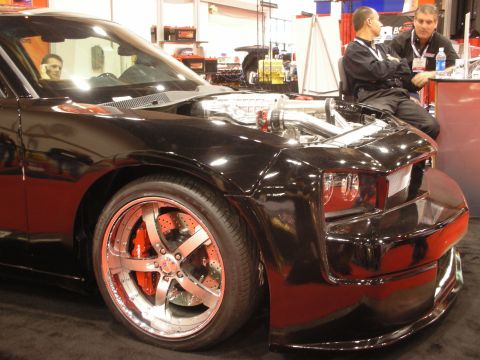 1998 Ford Crown Victoria - Front quarter of a black custom car with hood removed exposing a polished supercharged engine, big red brake calipers and chrome wheels at…