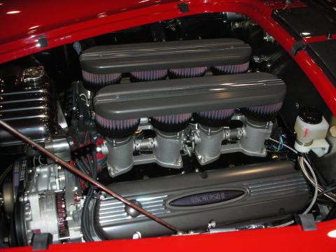1998 Ford Crown Victoria - Engine bay of a red car showing a V8 with stacked individual velocity-stack air filters and a Roush-branded valve cover.