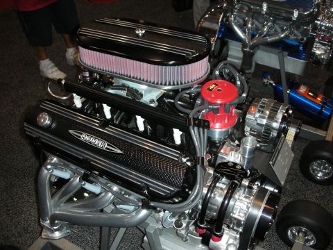 1998 Ford Crown Victoria - built V8 crate engine with a round chrome air cleaner, Roush valve covers, headers and red distributor cap displayed on a stand.