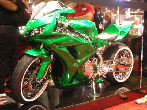 1998 Ford Crown Victoria - vivid green metallic custom sportbike with heavy chrome and a stretched swingarm displayed on a mirrored platform with onlookers.