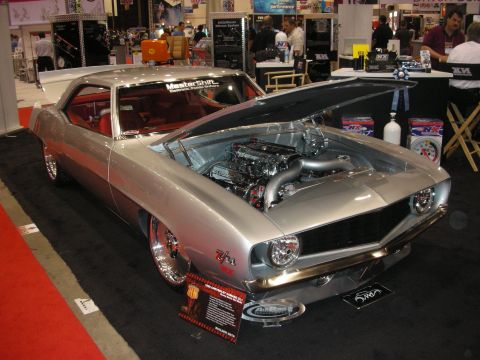 1998 Ford Crown Victoria - silver first-gen-style Camaro Z/28 with its hood off exposing a chrome engine, red interior visible, displayed under a MasterShift banner.