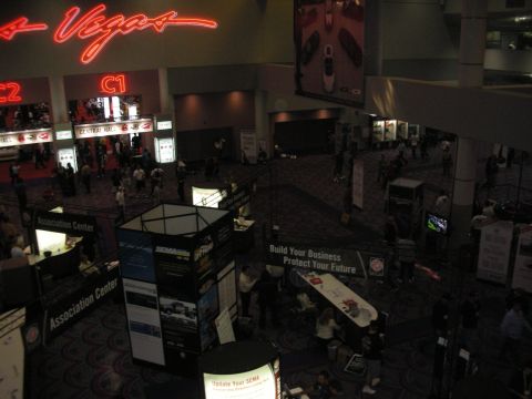 1998 Ford Crown Victoria - Crowded convention lobby with a red neon 'Vegas' sign overhead and business-themed exhibitor booths below.