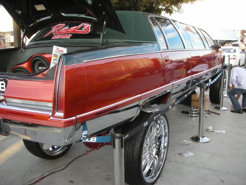 1998 Ford Crown Victoria - Custom maroon-and-black stretched wagon limo with chrome trim raised on a display lift at an outdoor car show.