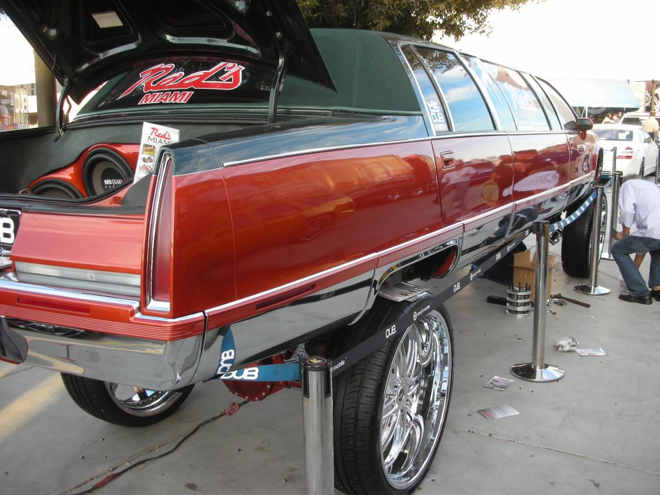 Maroon stretched station wagon limousine on a hydraulic lift outdoors