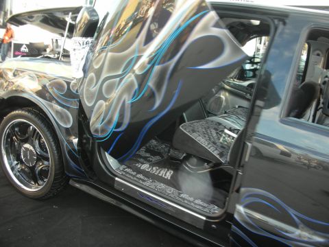 1998 Ford Crown Victoria - Custom black SUV with blue-outlined silver flame paint, billet wheels, and an open rear suicide door.