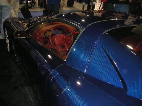 1998 Ford Crown Victoria - Close view of a blue carbon-fiber sports car's cockpit showing a red dashboard and steering wheel.