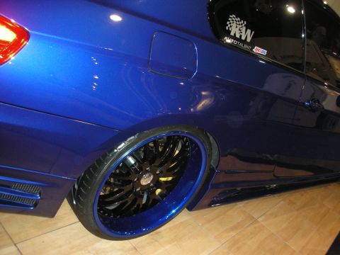 1998 Ford Crown Victoria - Lowered blue car's rear quarter showing a large black multi-spoke wheel with a blue lip on a tile floor.