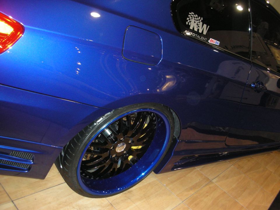 Rear quarter of a blue car with black-and-blue multi-spoke wheel