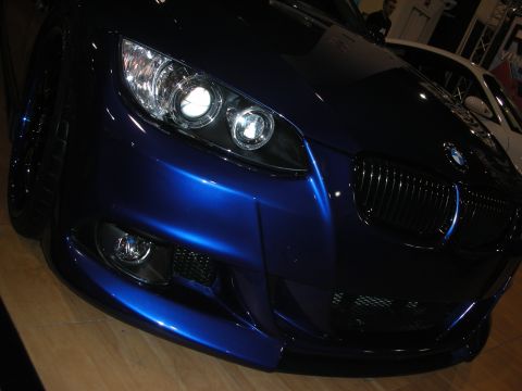 1998 Ford Crown Victoria - Low front close-up of a metallic blue BMW 3 Series coupe with halo headlights and kidney grille indoors.