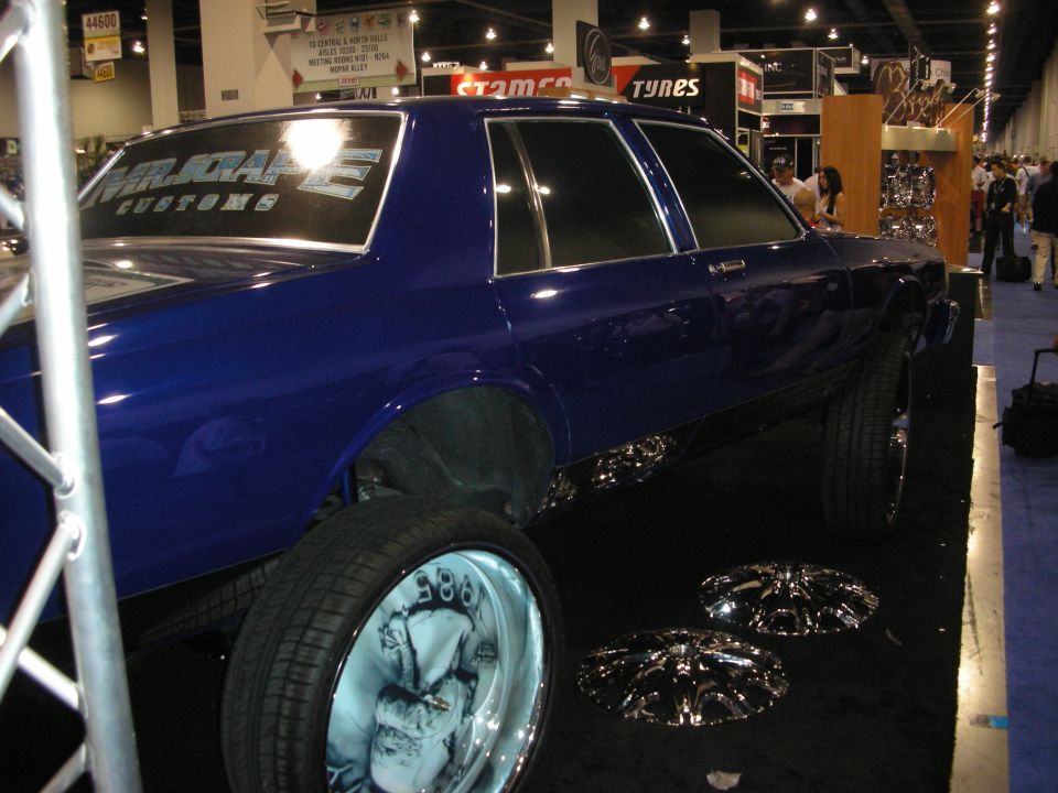 Blue box Chevrolet Caprice on tall wheels with chrome rims on floor